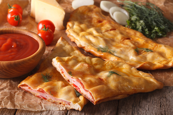 Cortar calzone pizza italiana con jamón de cerca y los ingredientes. Hori.
 - Foto, Imagen