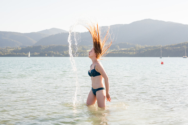 Mulher em Lake Flipping Wet Hair dramaticamente
 - Foto, Imagem