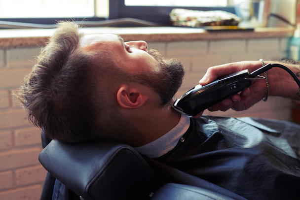 barber shaving beard with electric razor - Фото, зображення