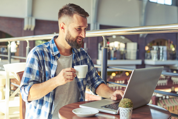 człowiek pije kawę i korzysta z laptopa w kawiarni - Zdjęcie, obraz