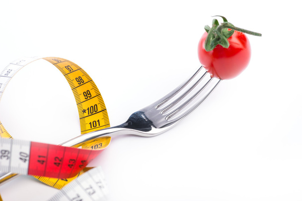 Forquilha, tomate e fita métrica sobre o fundo branco
 - Foto, Imagem