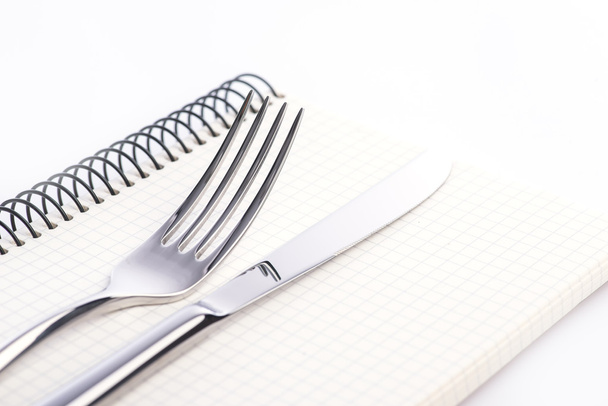 Forchetta, coltello e blocco note sullo sfondo bianco
 - Foto, immagini