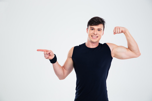 Happy man showing his biceps and pointing finger at copyspace - Фото, изображение