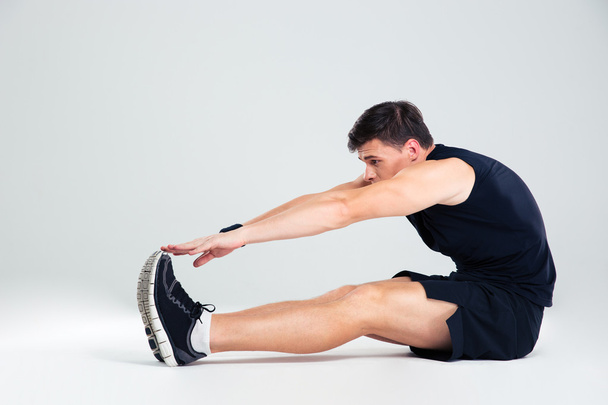 Portrait of athletic man doing stretching exercises - 写真・画像