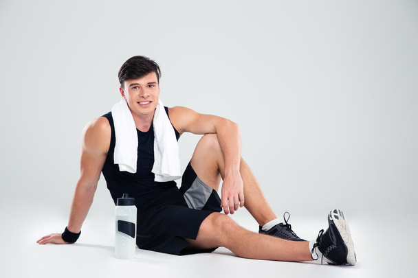 Smiling athletic man sitting on the floor - Foto, afbeelding