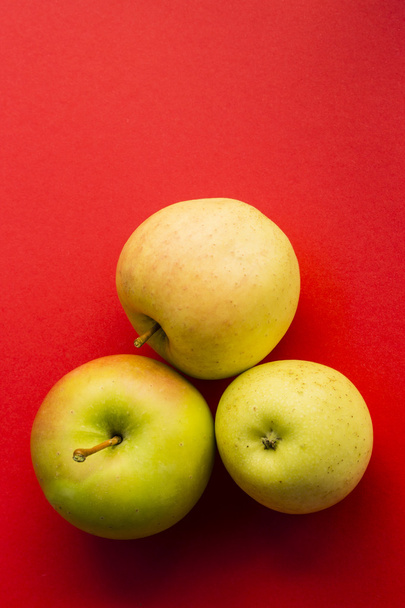 Green apples on red background - 写真・画像