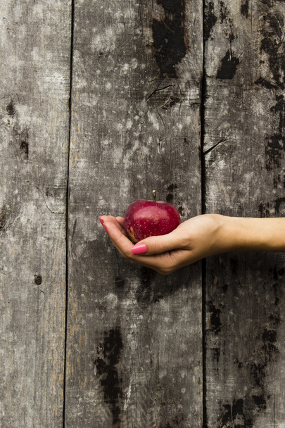 Manzana de mano femenina sobre fondo de madera
 - Foto, imagen