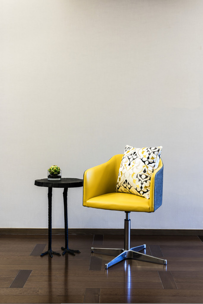 Деревянный стол желтое кресло сочетание перед простой стеной
 - Фото, изображение