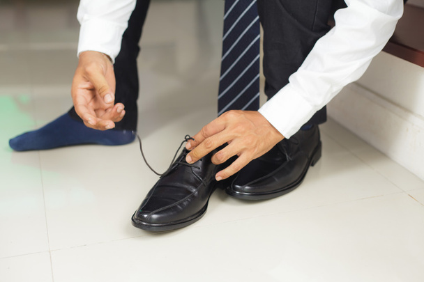 Man tying shoes indoors - Фото, зображення