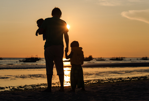 Vader en twee kinderen silhouetten op zonsondergang strand - Foto, afbeelding