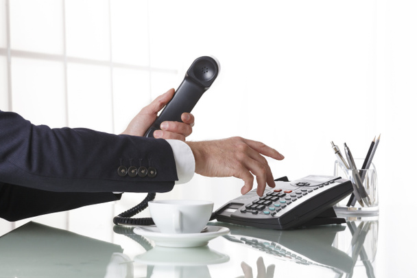 Businessman hands dialing out on a black deskphone - Foto, Imagen