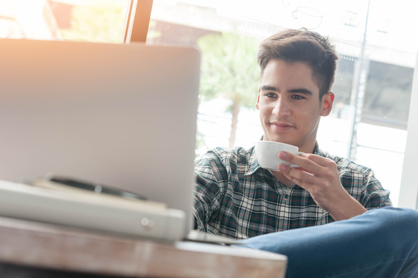 Uomo d'affari che beve caffè con computer portatile su tavolo di legno in caffè
 - Foto, immagini