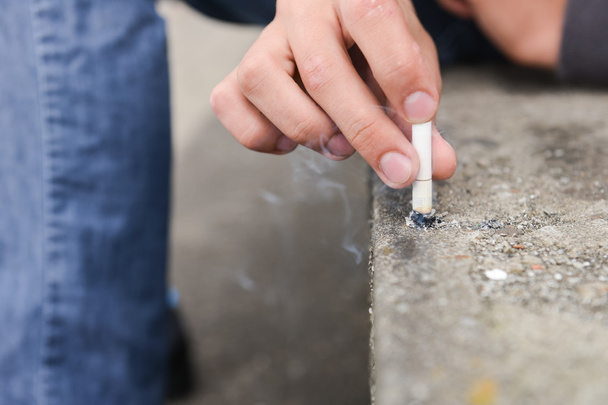 Hand of a young man extinguish cigarette on a stair - 写真・画像
