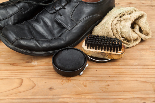 Vernis à chaussures avec brosse, tissu et chaussures d'homme usées sur plateau en bois
 - Photo, image