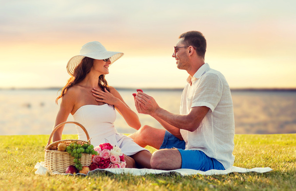 smiling couple with small red gift box on picnic - Foto, imagen