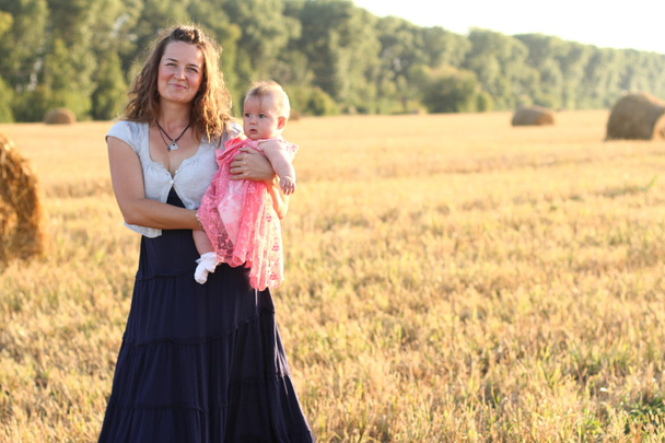 moeder bedrijf baby glimlachend op een tarweveld - Foto, afbeelding