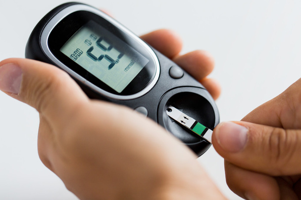 Zbliżenie człowieka sprawdzanie cukru we krwi przez glukometer - Zdjęcie, obraz