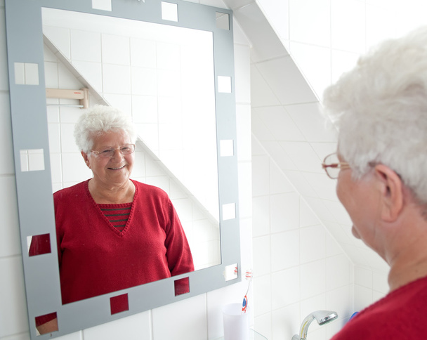 gepensioneerde m/v in de spiegel kijken - Foto, afbeelding