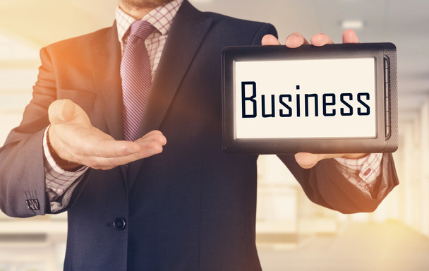 Бизнесмен показывает бизнес-концепцию на планшете стоя в офисе: Бизнес
 - Фото, изображение