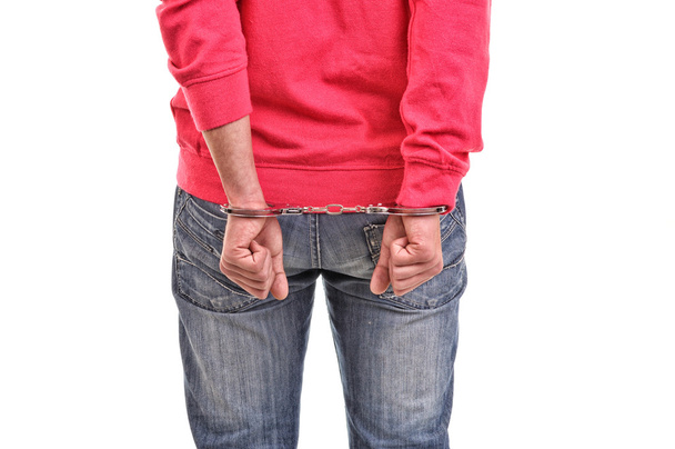 young man with pink blouse handcuffed with hands behind his back - 写真・画像