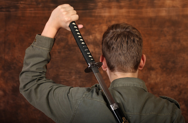 Mies, jolla on katana-miekka ruskealla batiikkitaustalla
 - Valokuva, kuva