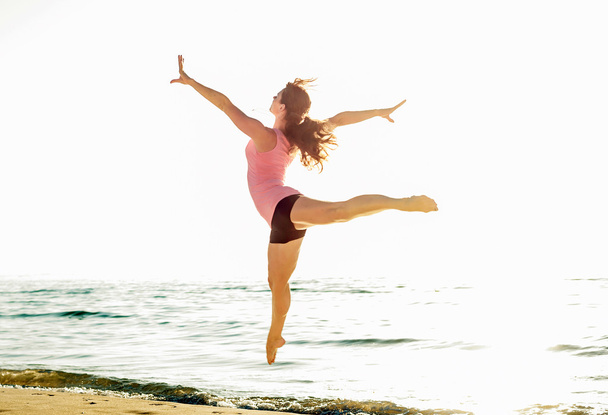 красива спортивна жінка стрибає на узбережжі, гімнастка робить
 - Фото, зображення