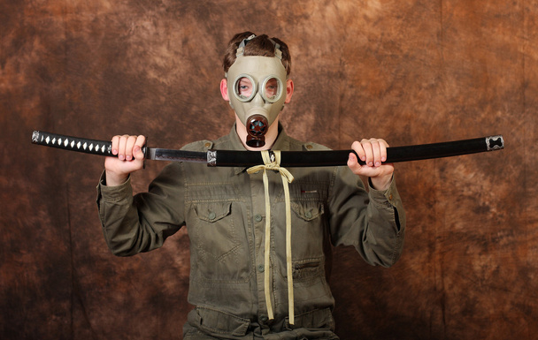 Homme avec masque à gaz et épée katana sur fond batik brun
 - Photo, image