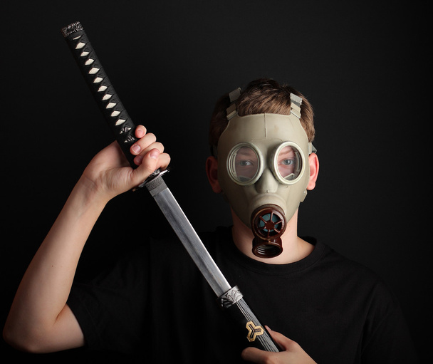 Чоловік з газовою маскою та мечем катани на чорному тлі
 - Фото, зображення