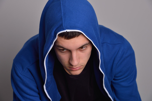 Portrait of a confident young man wearing blue hooded sweatshirt - Фото, зображення