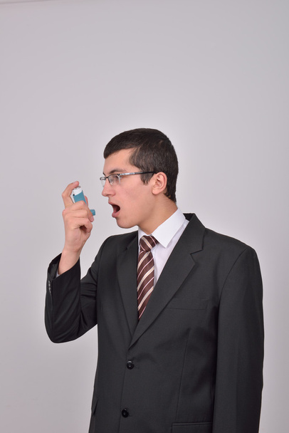 Young caucasian man in suit using an asthma inhaler to handle pr - Foto, afbeelding