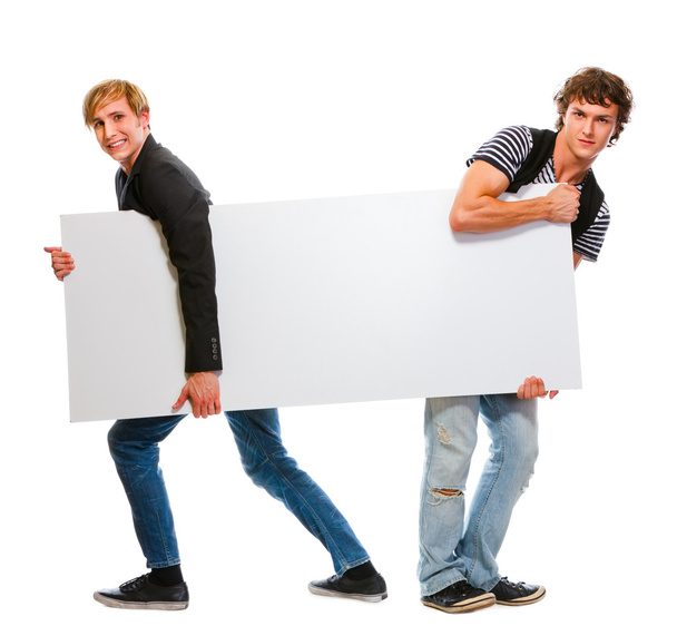 Two teenagers pulling blank billboard. Isolated on white - Φωτογραφία, εικόνα