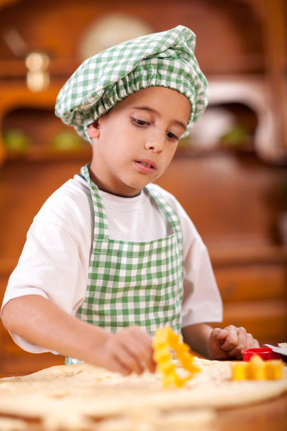 little boy kneading a dough to make cakes in the kitchen - Фото, зображення