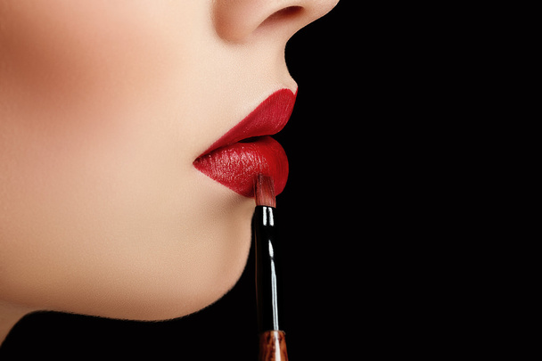 closeup macro photo of brush with lipstick and natural great red lips of young woman on black background - Foto, Imagem
