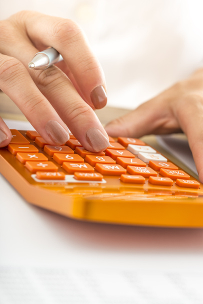 Closeup of female student hand calculating using orange desk cal - Φωτογραφία, εικόνα