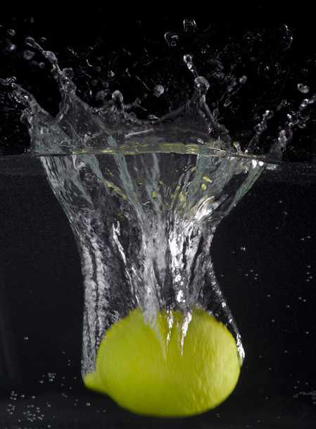 Tuore sitruuna putoaa veteen vesipisaralla mustalla pohjalla
 - Valokuva, kuva