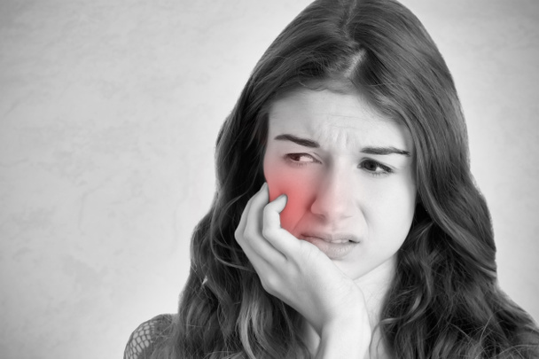 Gros plan d'une femme qui a mal à la dent. Noir et blanc avec une zone rouge autour de la douleur
. - Photo, image