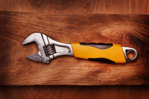 Adjustable wrench on wooden background - Fotó, kép