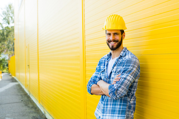 adulto trabajador con casco en pared amarillo - Foto, imagen