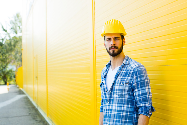 adult worker with helmet on yellow wall - Photo, image