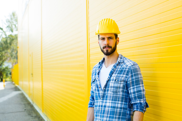 adult worker with helmet on yellow wall - Fotoğraf, Görsel