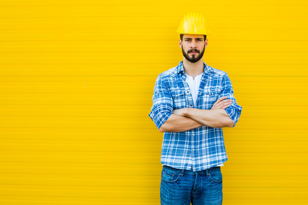adult worker with helmet on yellow wall - Zdjęcie, obraz