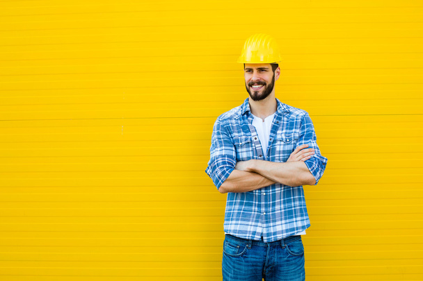 adult worker with helmet on yellow wall - 写真・画像
