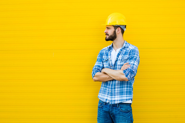 adult worker with helmet on yellow wall - Zdjęcie, obraz