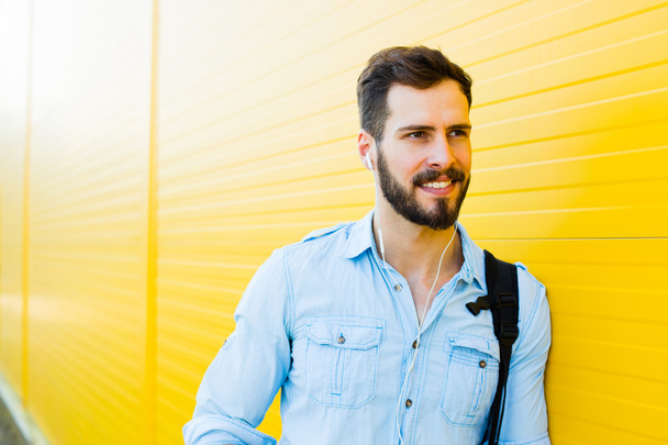 handsome man with backpack on yellow - Foto, afbeelding