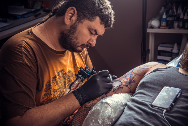 Professionele tattoo kunstenaar maakt tatoeage in tattoo studio - Foto, afbeelding