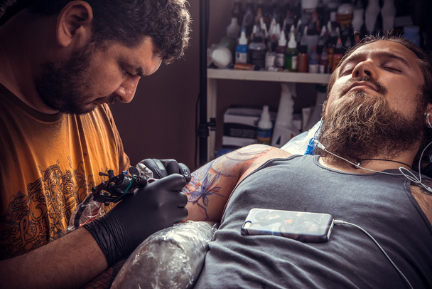 Maestro trabajando tatuajes en estudio de tatuajes
 - Foto, Imagen