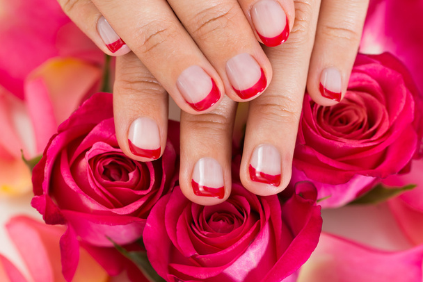 Mãos com verniz de unhas manicure colocado em rosas
 - Foto, Imagem