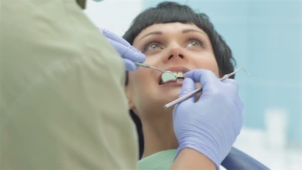 患者の上に立っての歯科医は、彼女の歯の検査 - 映像、動画