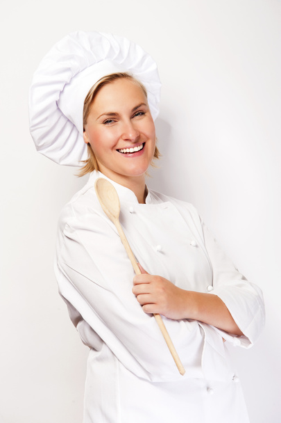 Femme chef en tenue de cuisine tenant une cuillère en bois et souriant à ca
 - Photo, image