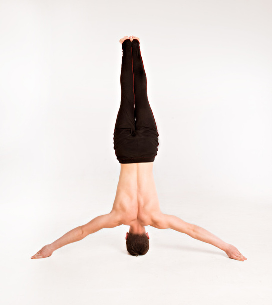 slender man doing gymnastic exercises. Gymnast standing on hands - Фото, изображение